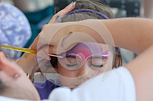 Little girl getting her face painted by face painting artist