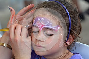 Little girl getting her face painted by face painting artist