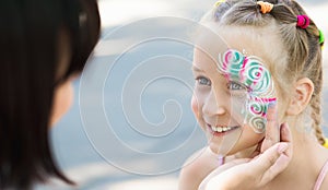 Little girl getting her face painted by face painting artist. photo