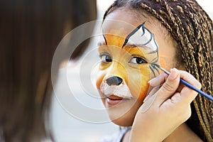 Little girl getting her face painted by face painting artist.