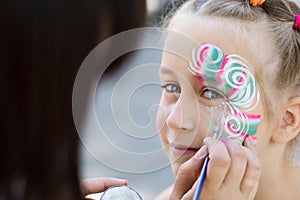 Little girl getting her face painted by face painting artist. photo