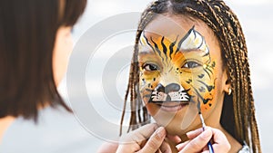 Little girl getting her face painted by face painting artist. photo