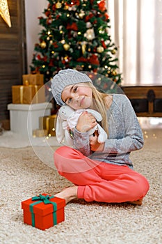 Little girl with gift box near Christmas tree on Christmas Eve at home