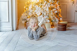 Little girl with gift box near Christmas tree at home