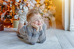 Little girl with gift box near Christmas tree at home