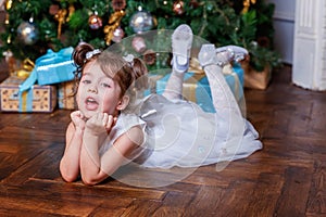 Little girl with gift box near Christmas tree at home