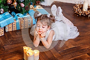 Little girl with gift box near Christmas tree at home