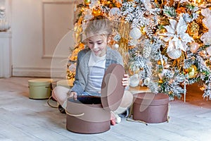 Little girl with gift box near Christmas tree at home