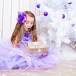 Little girl with a gift near Christmas tree
