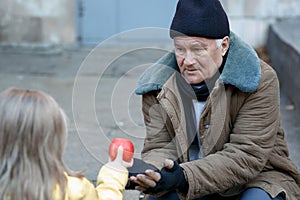 Little girl gives apple to the beggar