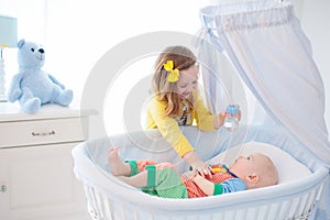 Little girl giving baby brother bottle with milk