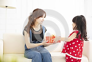 Little girl  giving a gift box to her mother