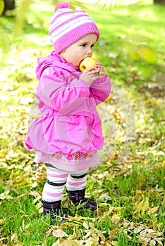 The little girl on a glade with an apple