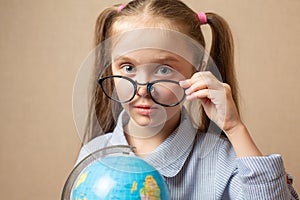 Little girl in glasses holding globe