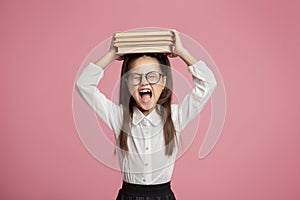 Little girl with glasses holds stack of books on her head and shouts