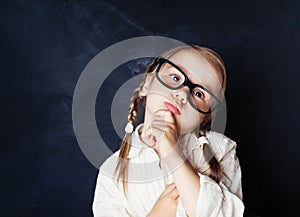 Little girl in glasses thinking on blue background