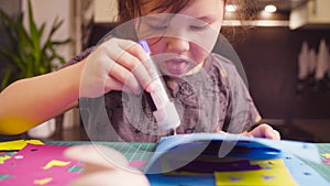 Little girl glueing colored paper