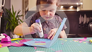 Little girl glueing colored paper