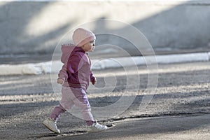 Little girl goes on the empty street. Child abandoned on street. Toddler walks alone