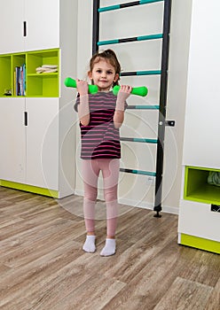 A little girl goes in for sports in her room.