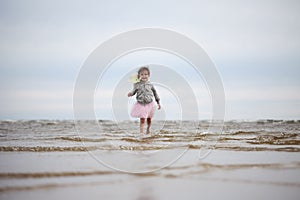 Little girl going in waves against sea and sky