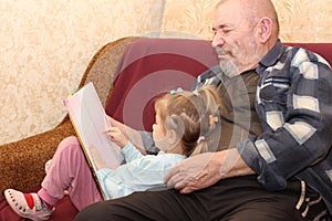 The little girl with the grandfather read the book