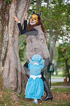 Little girl on grandma costume playing with her mom. Real family having fun while using costumes of the Little red riding hood