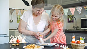 Little girl with grandma putting cream on cookies