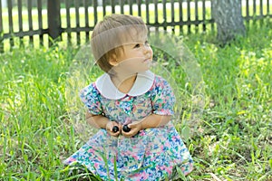 Little girl on green glade sitting and smiling with berries