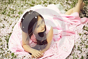 Little girl on green grass with petals