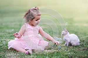 Little girl on the green grass playing with cat in park