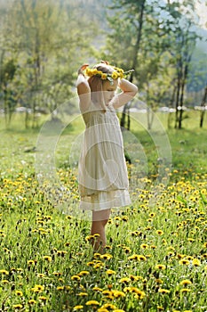 Little girl on green grass and summer flowers outdoors