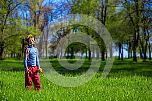 Little girl on a green grass in a wreath of flowers in spring