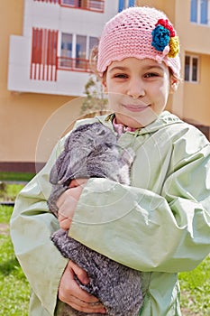 Little girl in greenish jacket holds rabbit