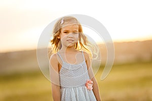 Little girl grey dress stand sloping wheat field