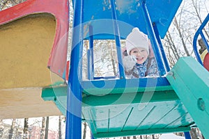 Little girl grimacing at winter outdoor playset tower