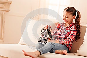 Little girl grinning broadly while having fun with robot toy