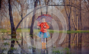 Little girl in gumboots in puddle