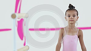 A little girl gymnast walks to a handrail and looks in the camera