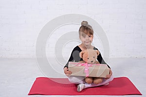 Little girl in the gymnastic swimsuit and with a teddy bear, free space