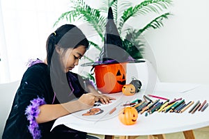 Little girl in halloween costume making jack-o-lantern