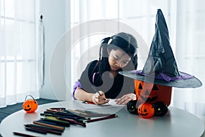 Little girl in halloween costume making jack-o-lantern