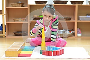 Little girl hand building tower made of montessori educational