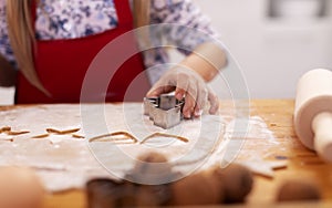 Little girl hand cutting gingerbread cookies from dough