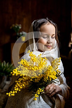 a little girl in a handkerchief with a mimosa