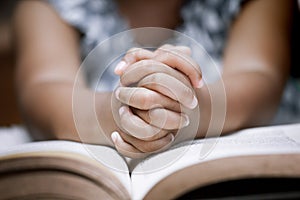 Little girl hands folded in prayer on a Holy Bible