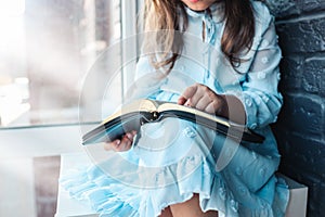 Little girl hands folded in prayer on a Holy Bible in church for faith concept in vintage color tone