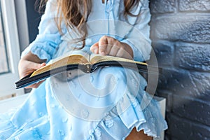 Little girl hands folded in prayer on a Holy Bible in church for faith concept in vintage color tone