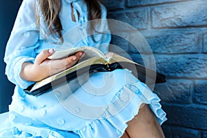 Little girl hands folded in prayer on a Holy Bible in church for faith concept in vintage color tone