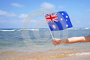 Little girl hands hold Australia flag against the sea horizon. 26th of January Independence day of Australia, concept.